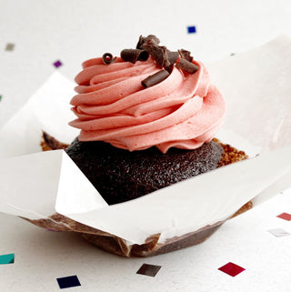 Vegan chocolate cupcake topped with vegan strawberry icing and chocolate curls.